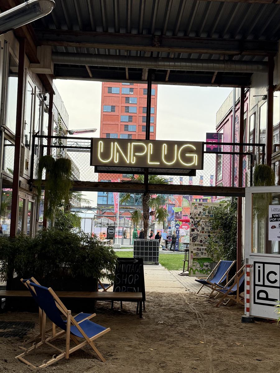 An UNPLUG neon sign and deck chairs in a covered courtyard at Strijp-S