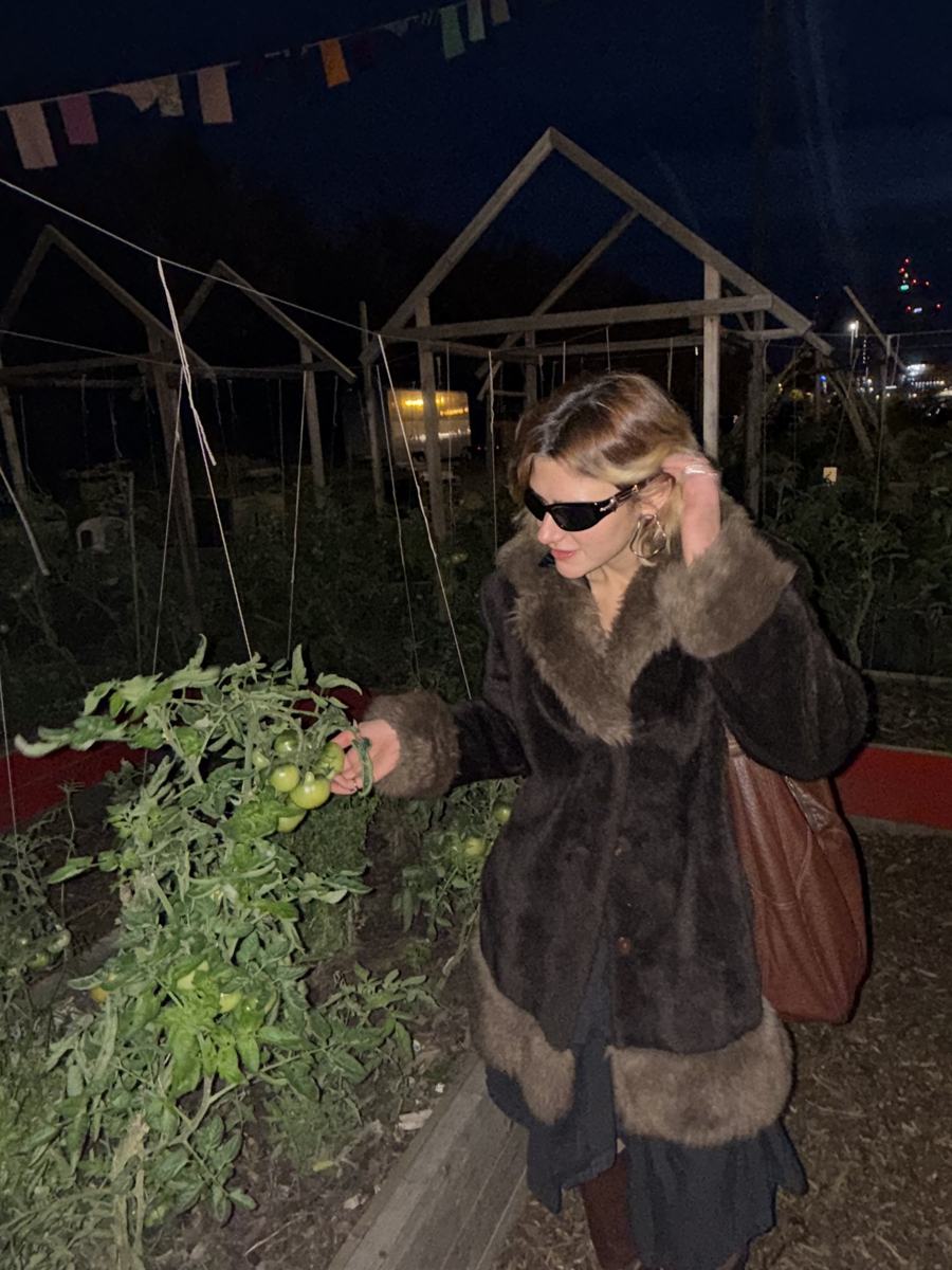 Katya in a vegetable garden at night, lit by a string of lights